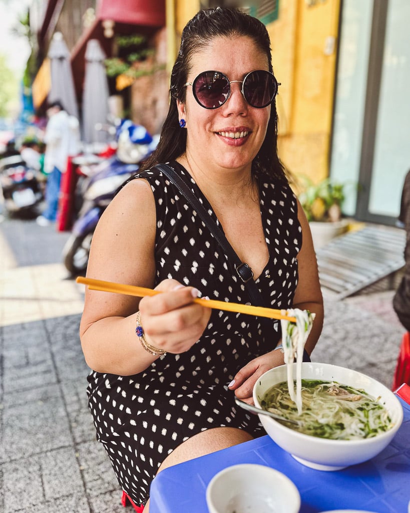 Bol fumant de phở servi dans un petit restaurant de rue à Ho Chi Minh City, avec chaises en plastique typiques.